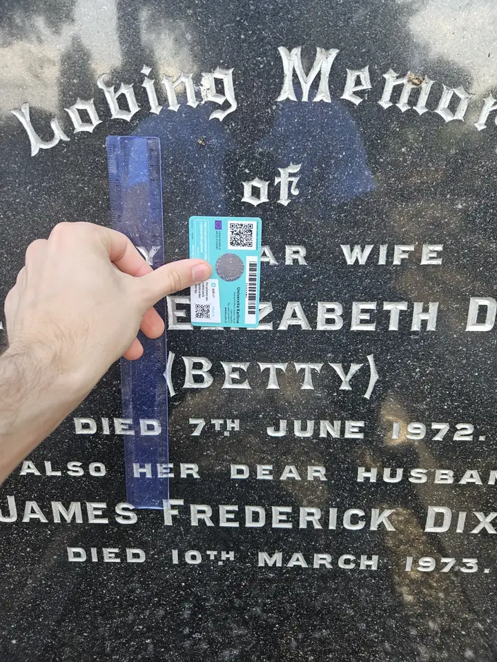 An evenly exposed dark gravestone with clear lettering and reference card