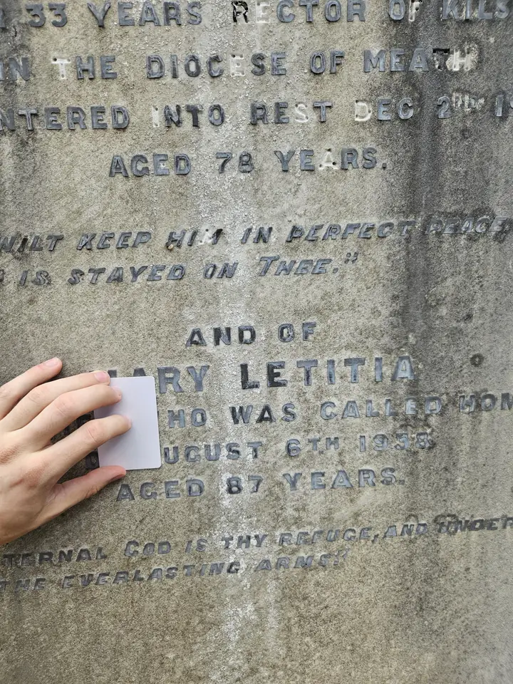 Several fingers covering the reference card against a gravestone